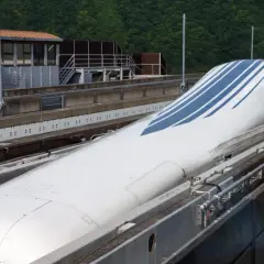 Der schnellste Zug Japans, ein Shinkansen, mit seiner aerodynamischen Nase und blauen Streifen, steht auf den Gleisen.