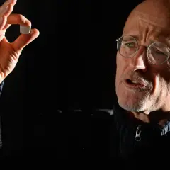 Mann mit Brille hält kleines Objekt, das an eine zukünftige Kopf transplantation erinnert.