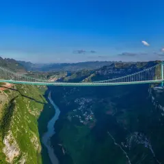 Die Huajiang Grand Canyon Bridge überspannt eine tiefe Schlucht mit einem Fluss. Die Brücke ist ein Meisterwerk der Ingenieurskunst in einer atemberaubenden Berglandschaft.
