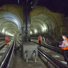 Arbeiter inspizieren den historischen Thames Tunnel. Die gewölbte Tunnelkonstruktion mit Gleisen und Beleuchtung ist beeindruckend.