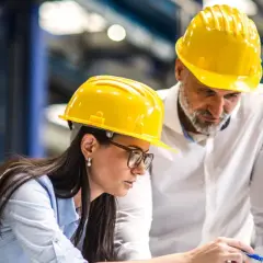 Zwei Bauingenieure mit gelben Helmen besprechen Pläne am Laptop. Sie planen, was ein Bauingenieur macht.