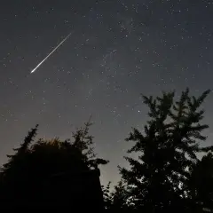 Ein heller Sternschnuppen-Streifen zieht sich über den sternenübersäten Nachthimmel. Perfekt, um die Perseiden zu beobachten.