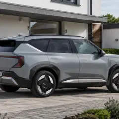 Silbernes Elektroauto der Marke Kia parkt vor einem modernen Haus.