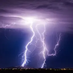 Gewitter physik: Mehrere Blitze erhellen den Nachthimmel über einer Stadt.