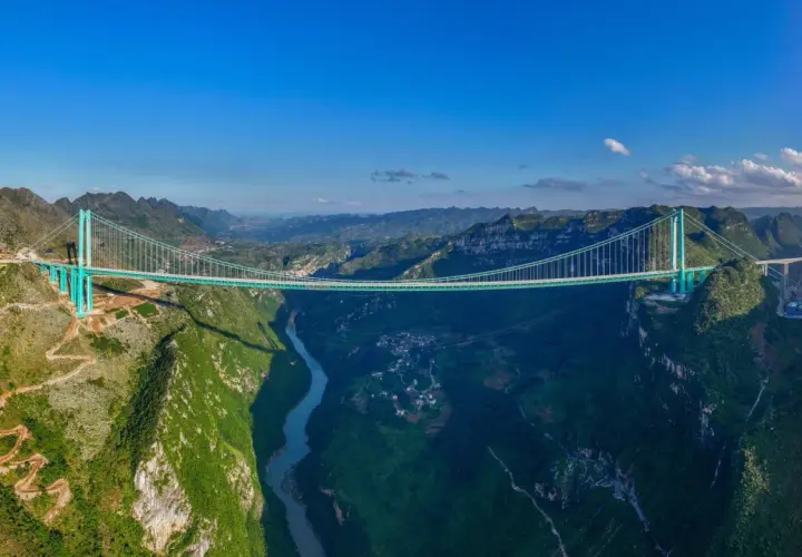 Die Huajiang Grand Canyon Bridge überspannt eine tiefe Schlucht mit einem Fluss. Die Brücke ist ein Meisterwerk der Ingenieurskunst in einer atemberaubenden Berglandschaft.