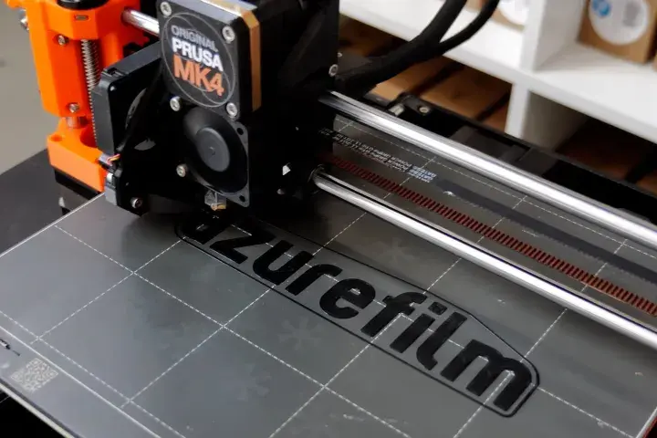 Ein 3D-Drucker wie dieser Prusa MK4 druckt Schicht für Schicht ein Objekt. Hier wird gerade das Logo "azurefilm" gedruckt.