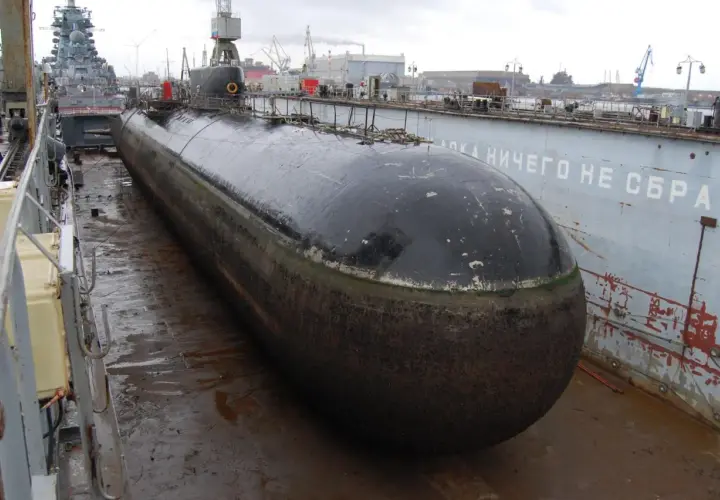 Ein riesiges U-Boot, das schnellste U-Boot der Welt, liegt im Trockendock. Im Hintergrund sind Kräne und andere Schiffe zu sehen.