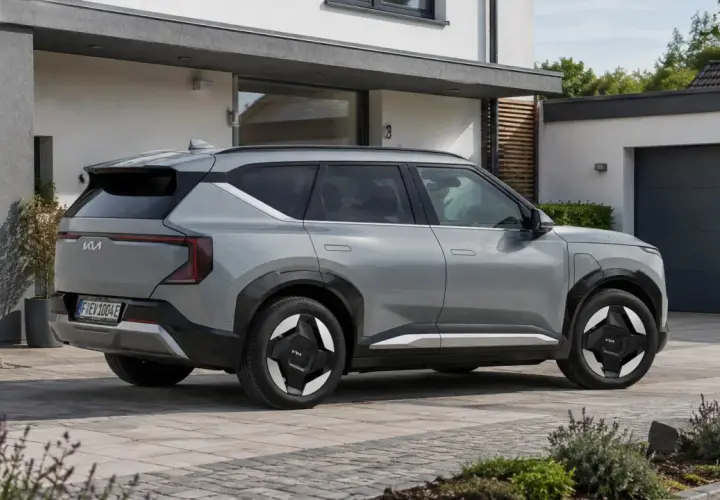 Silbernes Elektroauto der Marke Kia parkt vor einem modernen Haus.