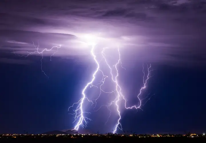 Gewitter physik: Mehrere Blitze erhellen den Nachthimmel über einer Stadt.
