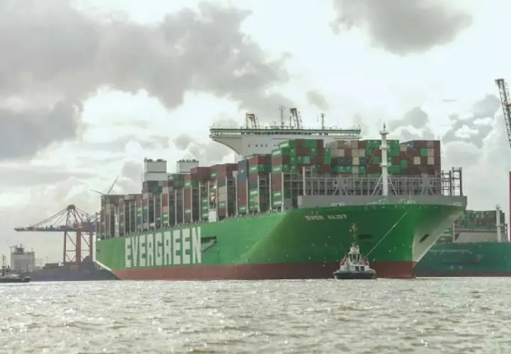 Das riesige Containerschiff "EVER ALOT" liegt im Hafen, beladen mit tausenden von Containern. Ein Schlepper assistiert.