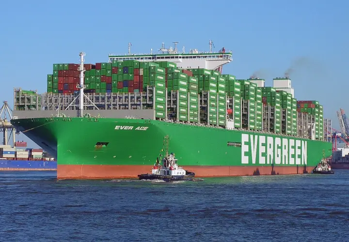 Ein riesiges grünes Containerschiff der Reederei Evergreen, die "Ever Age", wird von einem Schlepper durch das Wasser gezogen. Die technischen Daten sind beeindruckend.