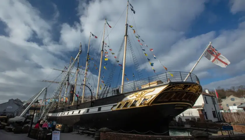 Das historische Schiff SS Great Britain, geschmückt mit bunten Flaggen, liegt im Hafen.