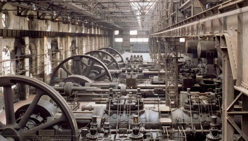 Reihen von riesigen Maschinen mit Schwungrädern in einer Fabrikhalle. Ein Blick in die Zeit, wann war die Industrialisierung?