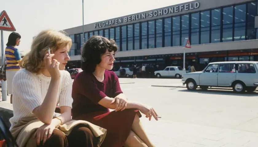 Zwei Frauen rauchen vor dem Flughafen Berlin-Schönefeld. Die Bauzeit des Flughafens war lang, aber die Aussicht ist es wert.