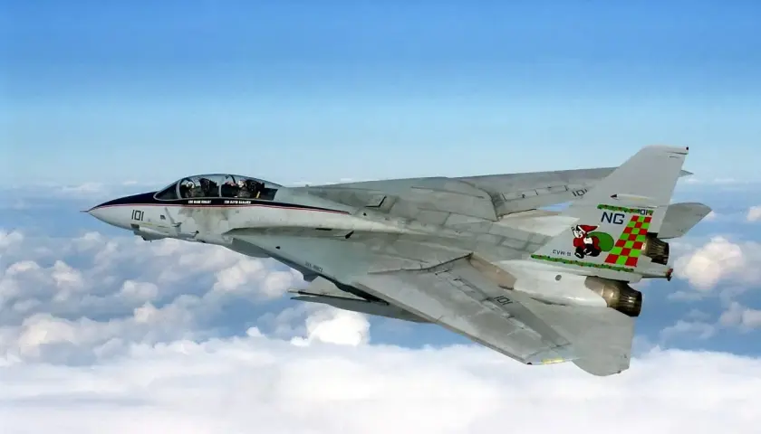 Ein schnelles Flugzeug, eine F-14 Tomcat, fliegt über den Wolken. Das Flugzeug hat eine markante Lackierung mit einer Figur auf dem Heck.