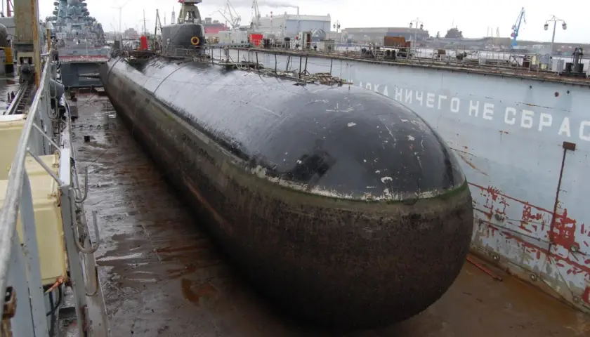 Ein riesiges U-Boot, das schnellste U-Boot der Welt, liegt im Trockendock. Im Hintergrund sind Kräne und andere Schiffe zu sehen.