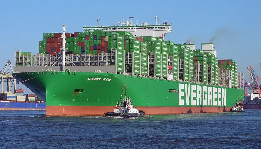 Ein riesiges grünes Containerschiff der Reederei Evergreen, die "Ever Age", wird von einem Schlepper durch das Wasser gezogen. Die technischen Daten sind beeindruckend.