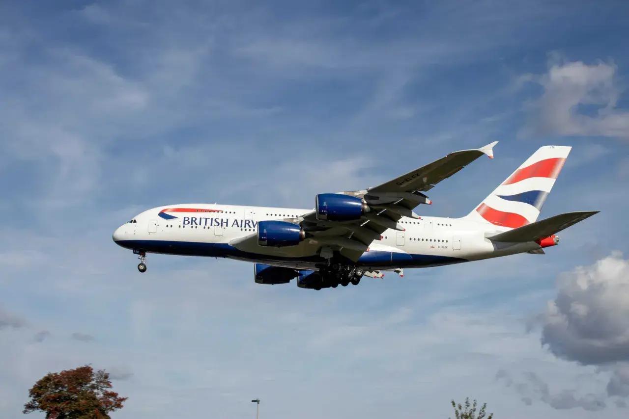 Ein riesiges British Airways Flugzeug mit vier Triebwerken fliegt im blauen Himmel. Wie lang ist ein Flugzeug dieser Größe? Über 70 Meter!
