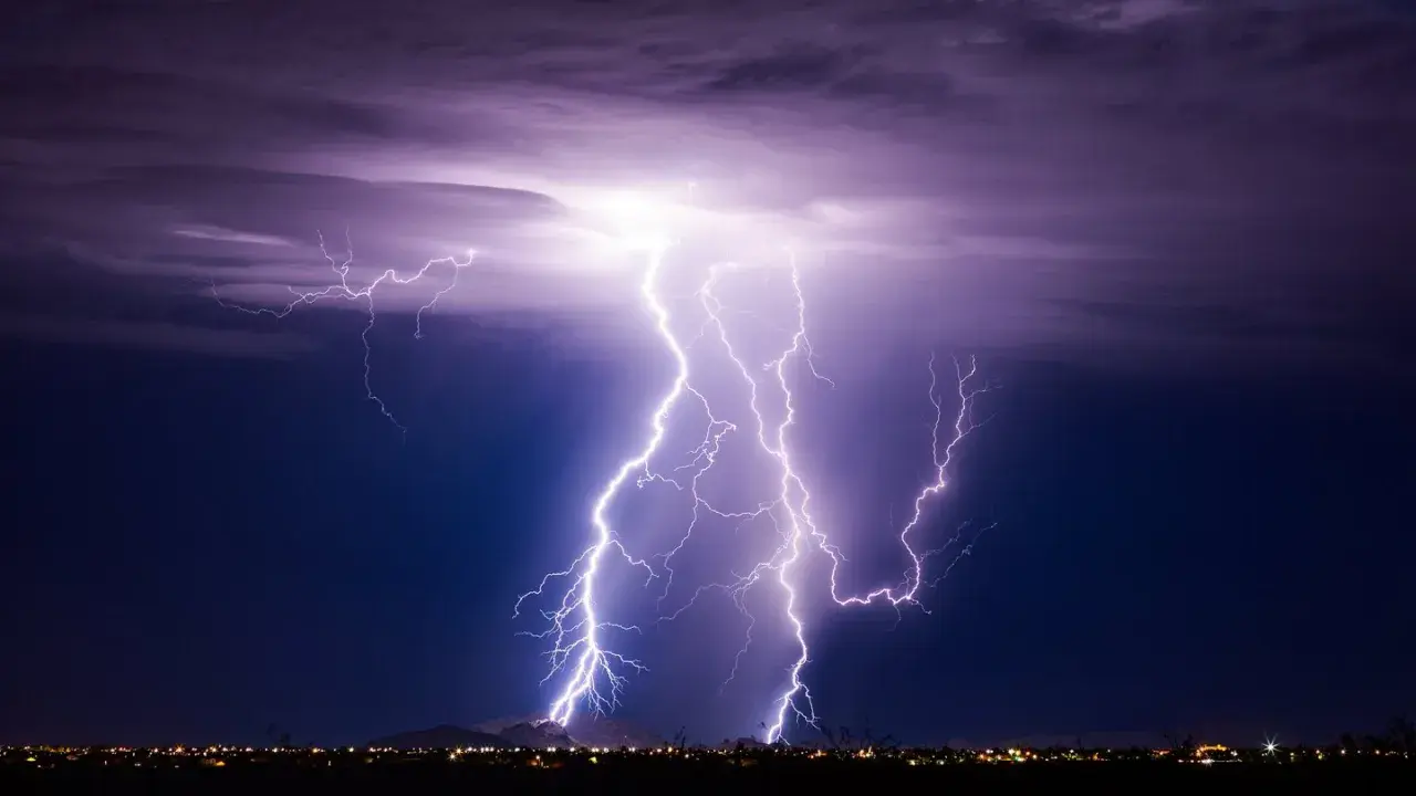 Gewitter physik: Mehrere Blitze erhellen den Nachthimmel über einer Stadt.