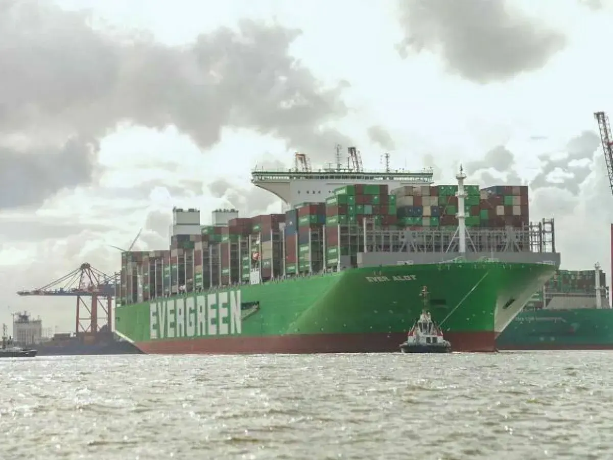 Das riesige Containerschiff "EVER ALOT" liegt im Hafen, beladen mit tausenden von Containern. Ein Schlepper assistiert.