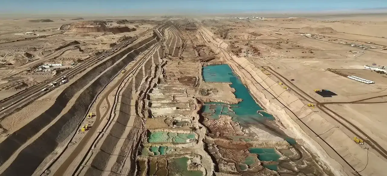 Gigantische Baustelle in der W&uuml;ste, die an ein k&uuml;nstliches Flussbett erinnert. Die Kritik an Neom wird durch die Ausma&szlig;e und den Ressourcenverbrauch deutlich.