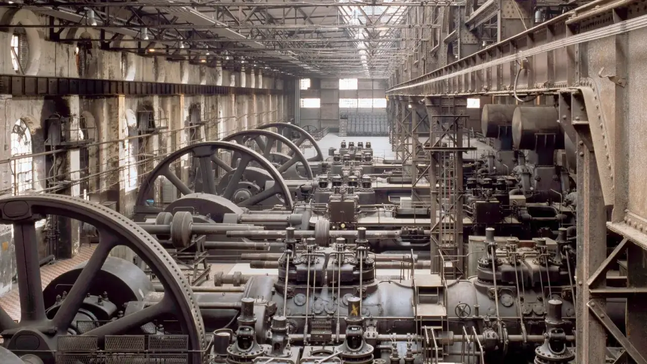 Reihen von riesigen Maschinen mit Schwungr&auml;dern in einer Fabrikhalle. Ein Blick zur&uuml;ck, wann war die Industrialisierung?